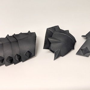 以下が含まれることがあります： スパイクが付いた黒いプラスチック製のアーマーのセット。アーマーはコスプレやコスチューム用にデザインされています。