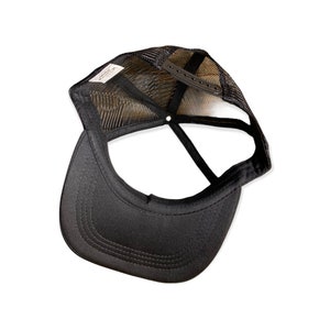 Op de afbeelding: Zwarte truckerpet met een mesh achterkant en een gebogen klep. De pet heeft een snapback sluiting voor verstelbare maatvoering. De binnenkant heeft een label met tekst. Deze pet is ontworpen voor casual wear en bescherming tegen de zon.