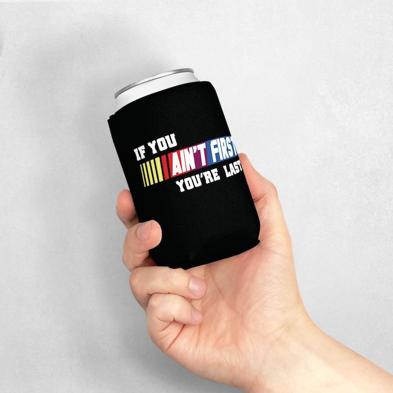 Pu&ograve; includere: Un portabicchieri nero con la scritta "IF YOU AIN'T FIRST YOU'RE LAST" in bianco, giallo, rosso, blu e viola. Il portabicchieri &egrave; progettato per mantenere le bevande fredde.