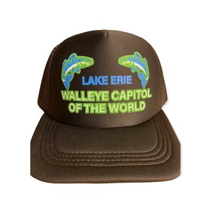 Op de afbeelding: Bruine truckerpet met een mesh achterkant en een gebogen klep. De voorkant toont de tekst "LAKE ERIE WALLEYE CAPITAL OF THE WORLD" in blauw en groen, met twee visillustraties.