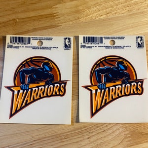 May include: Two Golden State Warriors static cling decals. Each decal features a blue silhouette of a basketball player with the team's logo and the words "WARRIORS" in a yellow, orange, and blue color scheme.
