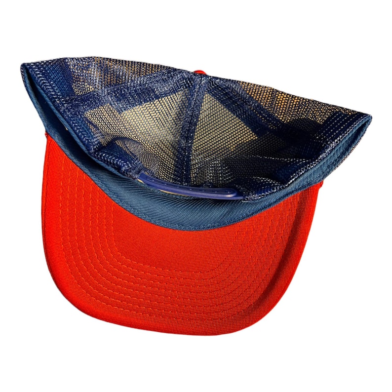 Op de afbeelding: Een rode en blauwe baseballpet met een mesh achterkant. De pet is binnenstebuiten gekeerd, waardoor de mesh voering zichtbaar is.