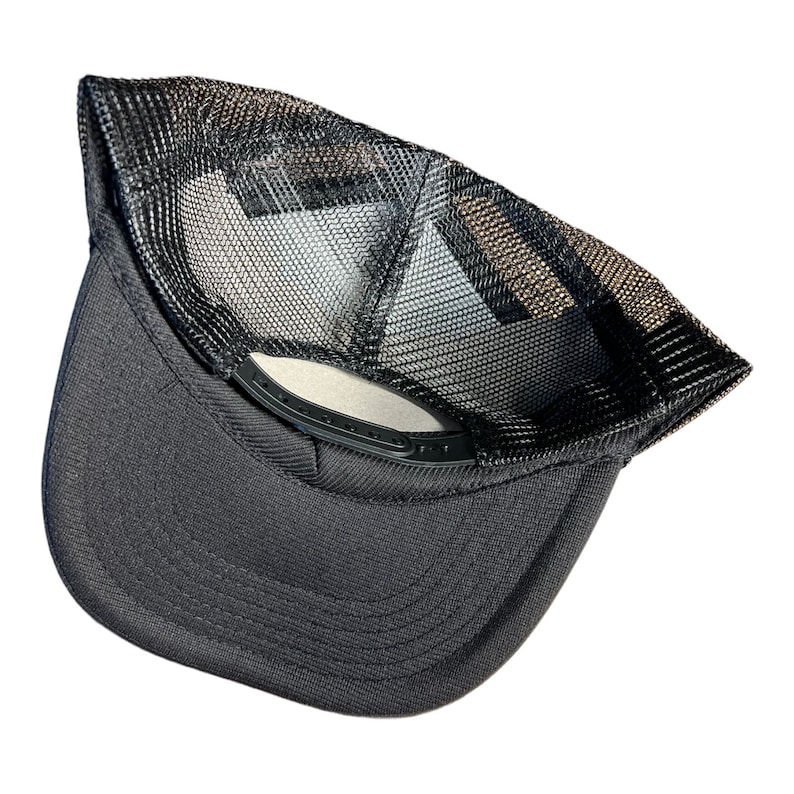 Op de afbeelding: Zwarte mesh truckercap met een zwarte klep en een zwarte verstelbare band. De pet is binnenstebuiten gekeerd om de mesh-rug te laten zien.