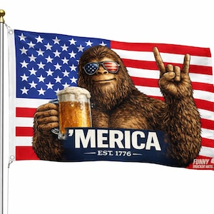 Puede incluir: Una bandera con un Sasquatch de dibujos animados con gafas de sol con un diseño de bandera estadounidense, sosteniendo una jarra de cerveza. La bandera tiene el texto "'MERICA EST. 1776" en una pancarta azul.