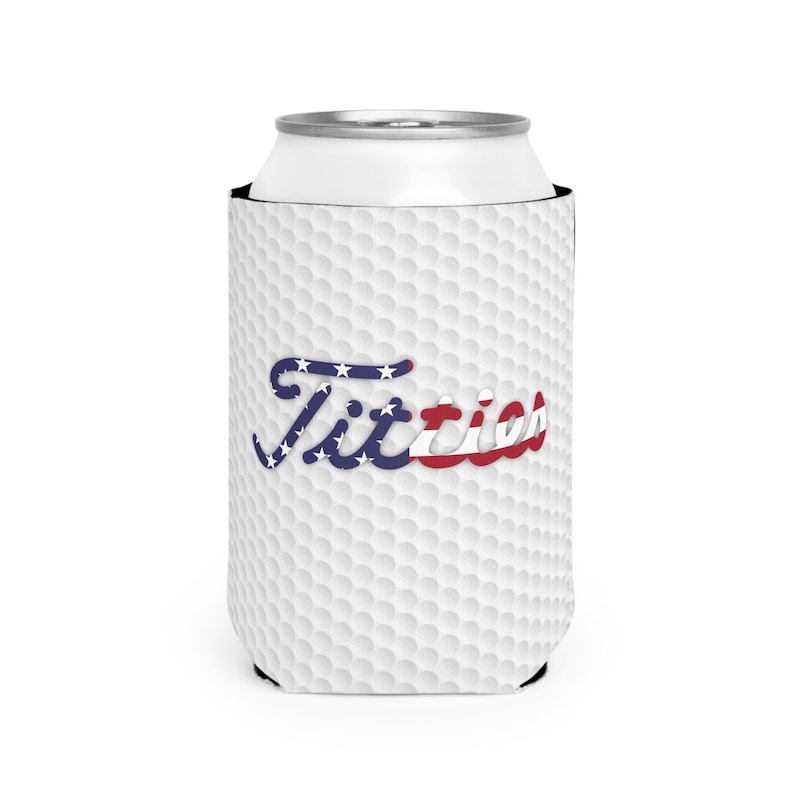May include: White golf ball patterned can cooler with the word "Titties" in blue and red lettering with a design resembling the American flag.