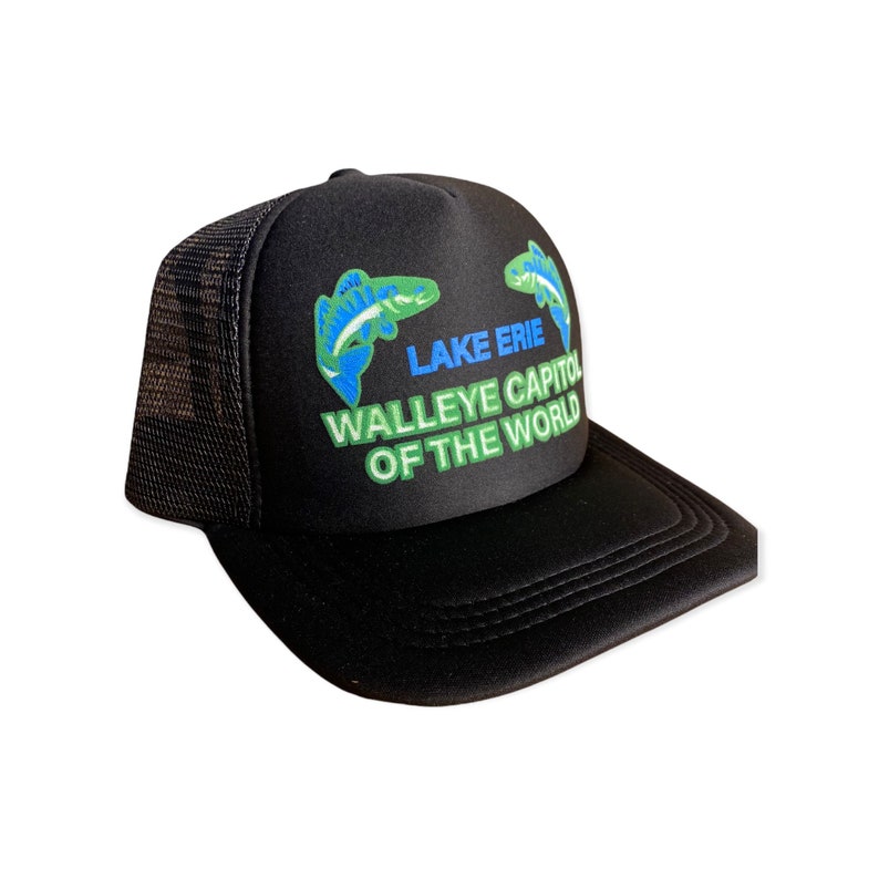 Op de afbeelding: Zwarte truckerpet met een gebogen klep en mesh achterkant. De pet toont de tekst "Lake Erie Walleye Capitol of the World" in groen en blauw, samen met twee visillustraties in groen en blauw.