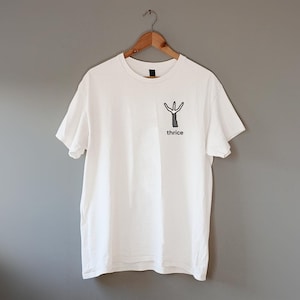 Puede incluir: Camiseta blanca con un gráfico en blanco y negro de un árbol estilizado con la palabra "thrice" debajo.