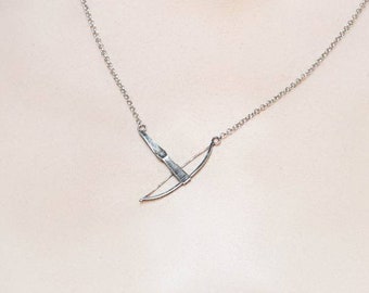 Puede incluir: Un collar de plata con un delicado colgante de arco y flecha.