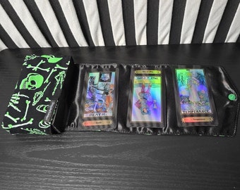 May include: Three tarot cards in a black and green pouch. The cards are Death, Five of Cups, and Temperance. The cards are iridescent and have a black background with gold accents.