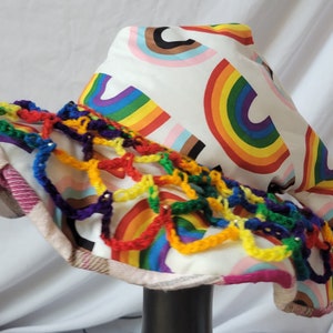 May include: A white sun hat with a rainbow pattern and a crocheted trim in rainbow colors.