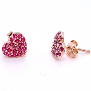 May include: A pair of rose gold heart-shaped earrings with pink cubic zirconia stones.