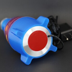 May include: Blue and red rocket-shaped night light with a silver base and a cord for plugging into an outlet.
