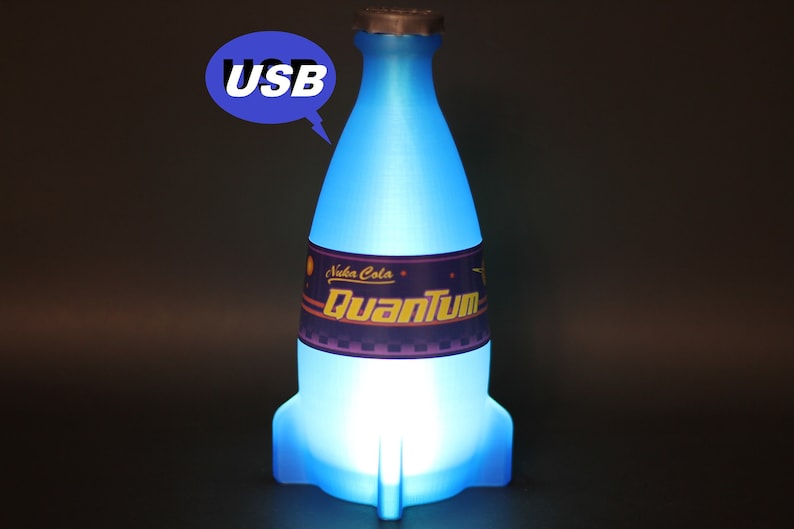 May include: A blue, rocket-shaped bottle with a label that reads "Nuka Cola Quantum". The bottle is lit from within, and has a USB plug on the top.
