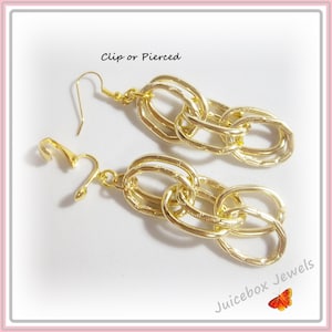 May include: Gold chain link earrings with a clip or pierced option. The earrings are long and dangle. The earrings are made of gold metal and have a textured finish.