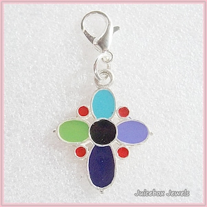 May include: A silver-toned charm with a cross-shaped design. The charm features colorful enamel in shades of blue, green, purple, and red, with a black center. It has a lobster clasp for easy attachment. The text "Juicebox Jewels" is in the bottom right corner.