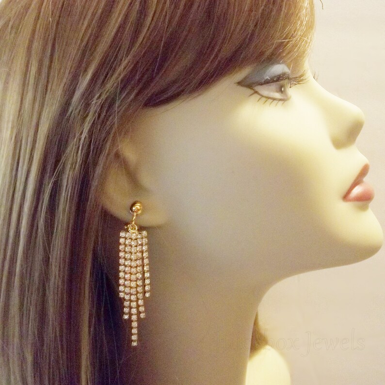 May include: Gold tone dangle earrings with a cascade of clear rhinestones.
