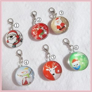May include: A collection of six Christmas-themed charms with silver-tone clasps. Each charm features a different festive design, including Santa Claus, a snowman, a reindeer, and an owl wearing a Santa hat. The charms are round and encased in clear glass.