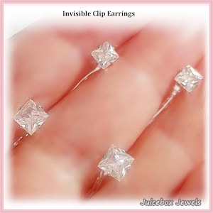 May include: Invisible clip earrings with square, clear gemstones. The earrings are set on thin, curved metal posts. The image includes the text "Invisible Clip Earrings" and "Juicebox Jewels".