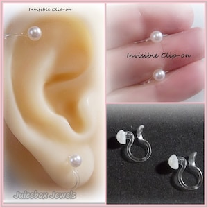 May include: A pair of white pearl clip-on earrings with clear plastic clips. The earrings are shown on a model's ear and on a white surface. The text "Invisible Clip-on" is visible in the image.
