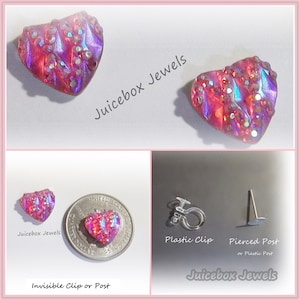 May include: A pair of iridescent pink heart-shaped earrings with a glittery finish. The earrings are shown with a plastic clip and a pierced post option. The text "Juicebox Jewels" is visible in the image.
