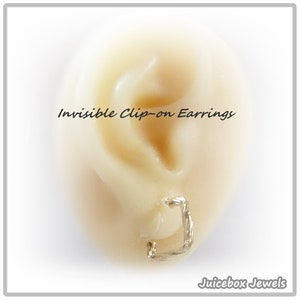May include: Close-up of a gold clip-on earring on a model ear. The earring is designed to be invisible when worn. The text "Invisible Clip-on Earrings" is visible above the earring. The text "Juicebox Jewels" is visible below the earring.