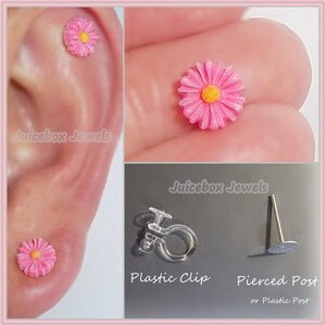 May include: Pink flower earrings with a yellow center. The earrings can be worn with a plastic clip or a pierced post.