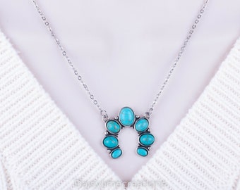 Puede incluir: Un collar de cadena de plata con un colgante de herradura turquesa. El colgante está hecho de varias piedras turquesas de forma ovalada.