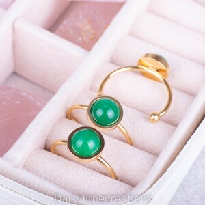 Peut inclure: Trois bagues en or avec des pierres précieuses vertes dans un écrin à bagues en velours blanc.