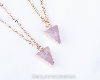 May include: Two gold chain necklaces with pink triangle pendants. The necklaces are layered and the pendants are slightly different sizes.