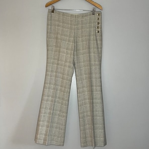 May include: A pair of plaid pants with a button detail on the side. The pants are a light brown and white color.