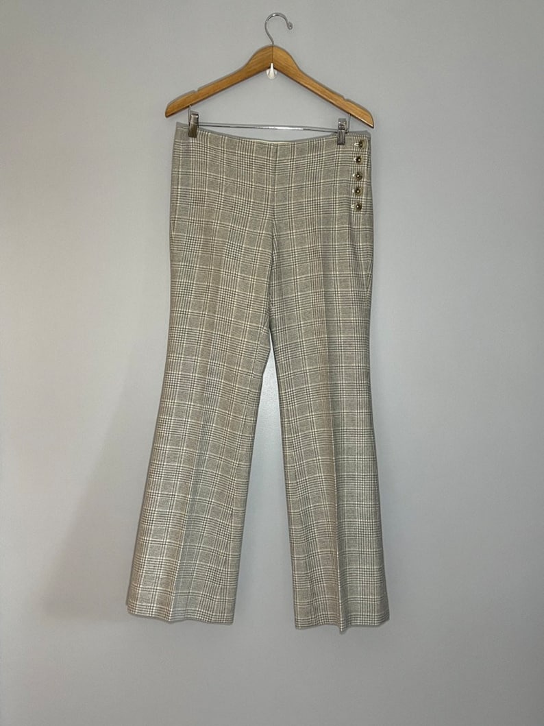 Peut inclure: Un pantalon &agrave; carreaux avec un d&eacute;tail boutonn&eacute; sur le c&ocirc;t&eacute;. Le pantalon est de couleur beige et blanc.