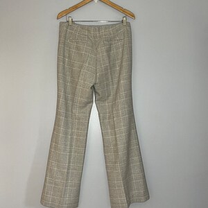 Peut inclure: Un pantalon &agrave; jambes larges &agrave; carreaux suspendu &agrave; un cintre en bois. Le pantalon est &agrave; carreaux brun clair et noir.