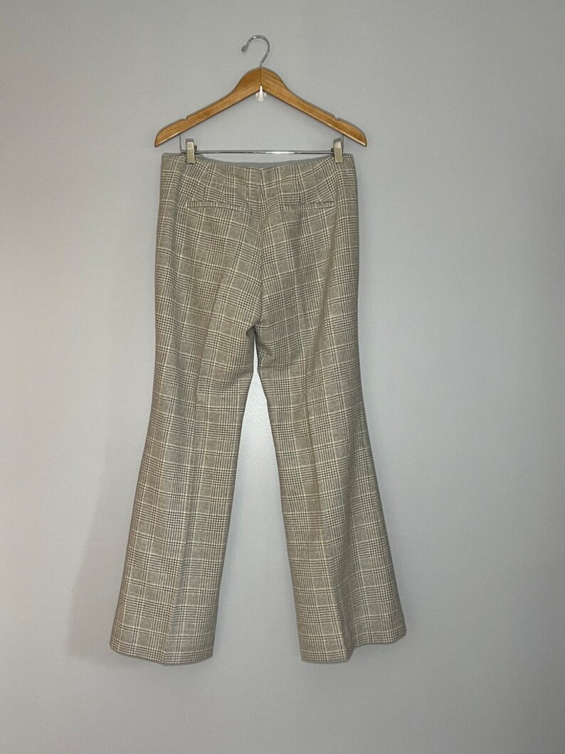 Peut inclure: Un pantalon &agrave; jambes larges &agrave; carreaux suspendu &agrave; un cintre en bois. Le pantalon est &agrave; carreaux brun clair et noir.