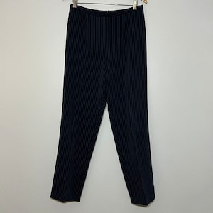 May include: Black pinstripe pants hanging on a wooden hanger. The pants have a straight leg and a zipper closure.