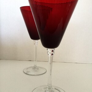 May include: Two red wine glasses with a clear stem and base. The glasses have a textured rim and are made by the company "By Moravia Crystal".