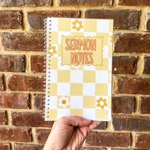 Op de afbeelding: Een spiraalgebonden notitieboek met een wit en lichtgeel ruitpatroon, voorzien van oranje bloempictogrammen en de tekst SERMON NOTES in oranje gedrukt binnen een golvende rechthoekige rand op de voorkant.