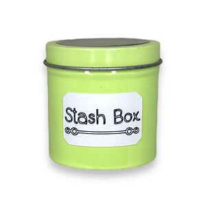 May include: A small, green metal tin with a white label that says "Stash Box".