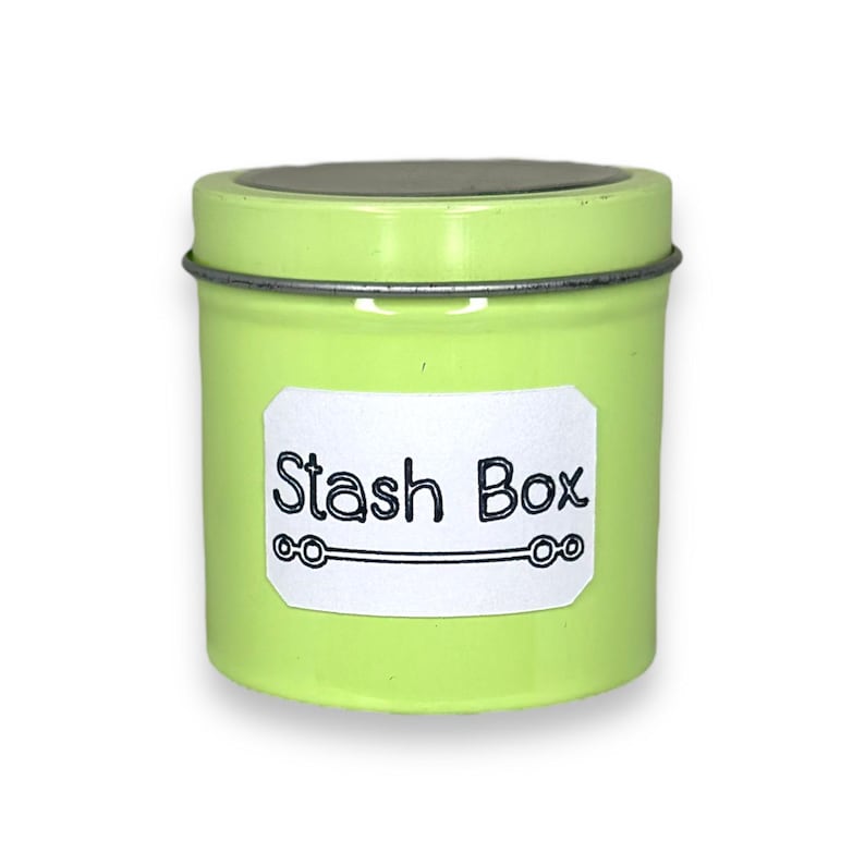 May include: A small, green metal tin with a white label that says "Stash Box".
