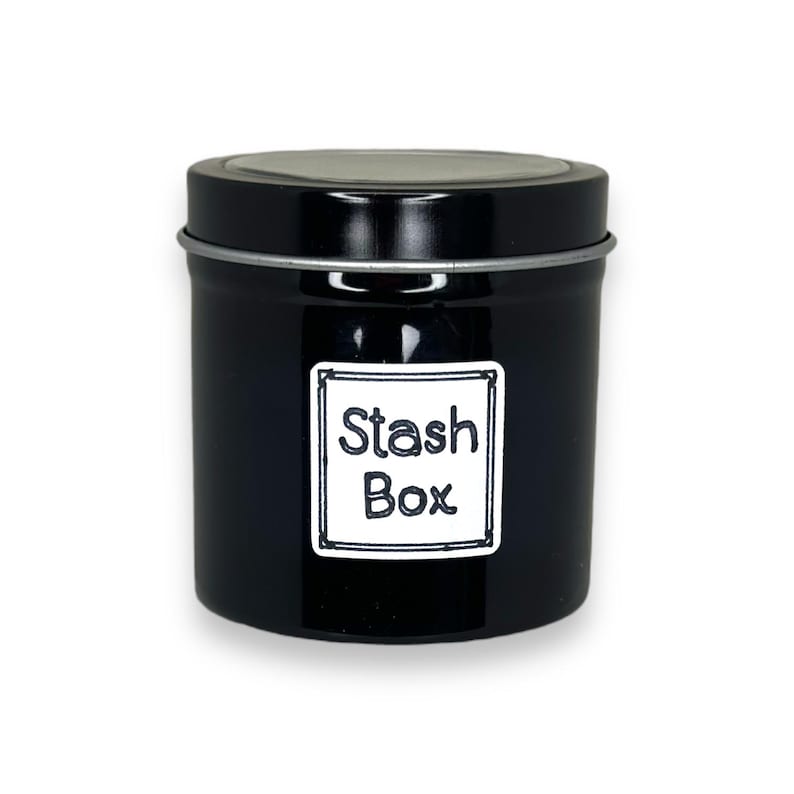 May include: A black metal tin with a silver rim and a white label that says "Stash Box".