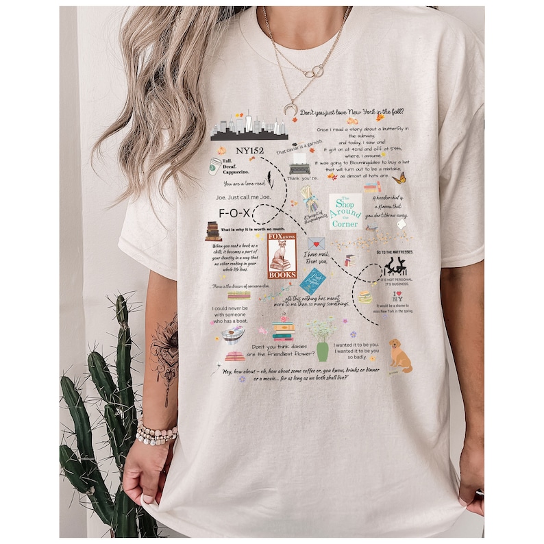 Pode incluir: Camiseta branca com um design gr&aacute;fico que apresenta um mapa da cidade de Nova Iorque com v&aacute;rios textos e ilustra&ccedil;&otilde;es. O texto inclui cita&ccedil;&otilde;es sobre a cidade de Nova Iorque, livros e caf&eacute;. As ilustra&ccedil;&otilde;es incluem uma raposa, uma borboleta, uma pilha de livros, uma ch&aacute;vena de caf&eacute; e uma flor.