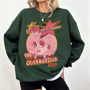 May include: Green sweatshirt with a vintage-style graphic of Jem and the Holograms. The graphic features a pink-haired Jem with a star on her ear, and the text "1987 Truly Outrageous Tour".