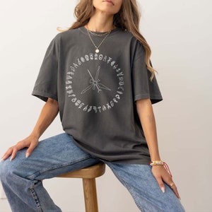 K&ouml;nnte beinhalten: Ein &uuml;berdimensioniertes T-Shirt in Anthrazitgrau mit einer wei&szlig;en Grafik eines Kreises mit verschiedenen Werkzeugen und dem Text "TAKE NOTE" um den Kreis herum.