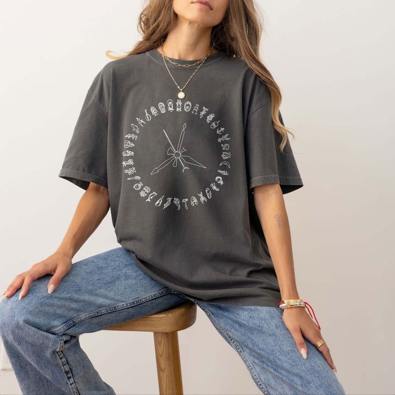 K&ouml;nnte beinhalten: Ein &uuml;berdimensioniertes T-Shirt in Anthrazitgrau mit einer wei&szlig;en Grafik eines Kreises mit verschiedenen Werkzeugen und dem Text "TAKE NOTE" um den Kreis herum.