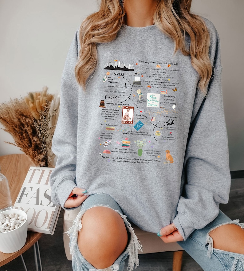 Pode incluir: Camisola de cor cinzenta com uma estampa gr&aacute;fica de um horizonte da cidade, livros e texto que diz "N&atilde;o apenas sonhe, seu trabalho &eacute; a mat&eacute;ria do outono".