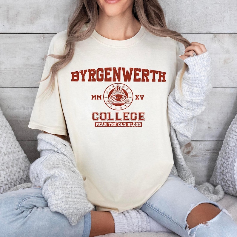 May include: A white t-shirt with a red graphic design that says "Byrgenwerth College" with an all-seeing eye logo and the text "Fear the Old Blood".