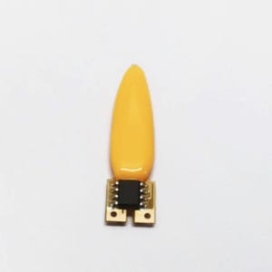 May include: A yellow, teardrop-shaped object with a black square component attached to a small circuit board. The object is set against a white background.