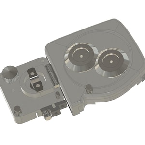 May include: A gray, mechanical device with two circular components and a hinged section. The device has multiple knobs and a textured handle. The design appears to be a technical or engineering component.