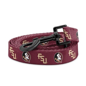 May include: Maroon and gold dog lead featuring the Florida State Seminoles logo and "FSU" text. The lead has a black metal clasp and is rolled up on a white background. The pattern repeats along the length of the lead.