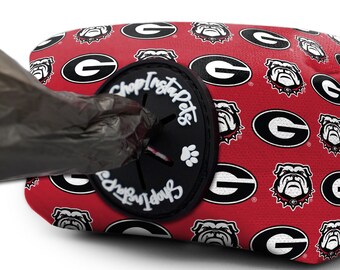 May include: Red dog poop bag dispenser with a black circle that says "Shop Insta Pets" and a paw print. The dispenser is covered in a pattern of white University of Georgia logos.