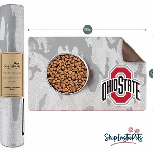 May include: A gray and white camouflage pet food mat, 29 inches long and 18 inches wide, with the Ohio State logo and a bowl of pet food. The mat is anti-slip, waterproof, and recyclable. The rolled-up matching mat is also visible.